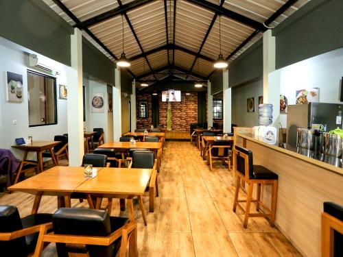 a restaurant with wooden tables and chairs and a bar at Super OYO Townhouse OAK Hotel Fiducia Pondok Gede in Jakarta