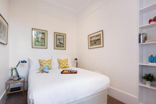 ロンドンにあるThe Stunning Philbeach Garden Apartmentの白いベッドルーム(白いベッド1台、棚付)
