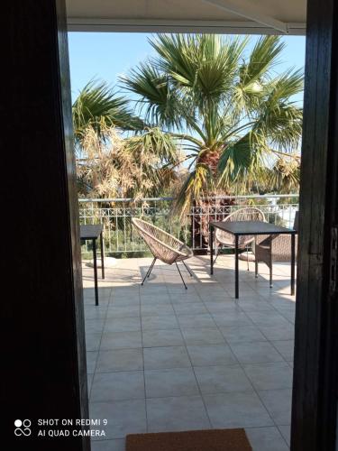 a patio with a table and chairs and a palm tree at Kis-Kis in Metókhion Ayías Kiriakís