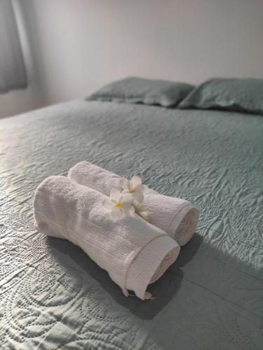 Una toalla en una cama con una flor. en Pousada Encanto dos Mares en Natal