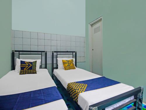 2 Betten nebeneinander in einem Zimmer in der Unterkunft SPOT ON 92219 Pondok Karisma Syariah in Tasikmalaya