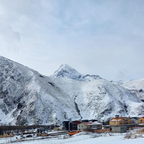 a snow covered mountain with a town in front of it at mood villa Kazbegi in Stepantsminda
