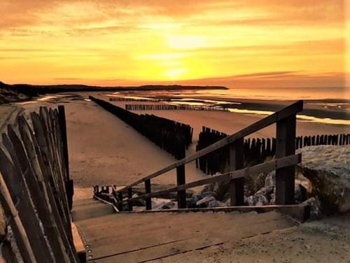 a wooden fence on a beach with a sunset at Au Spa d'eau pâle in Ferques