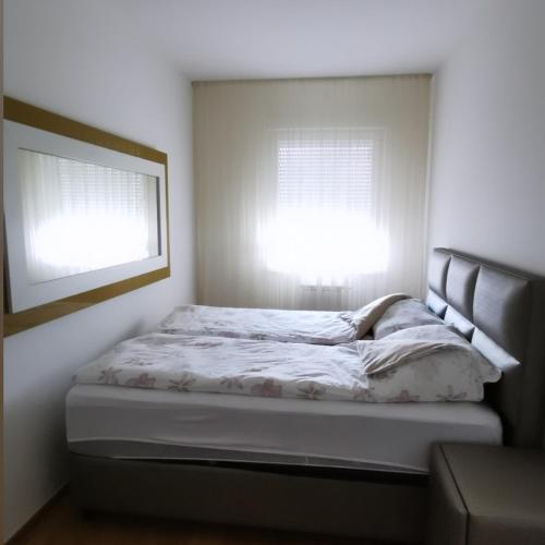 a bed in a white room with two windows at Alex LUX in Banja Luka