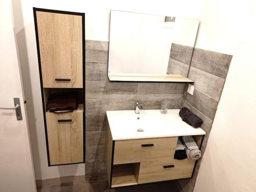 La salle de bains est pourvue d'un lavabo et d'un miroir. dans l'établissement Maison avec extérieur et arrivée autonome - Aurillac, à Aurillac
