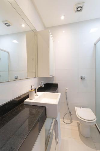a white bathroom with a sink and a toilet at Apartamento completo no centro de Belém, próximo de tudo! in Belém