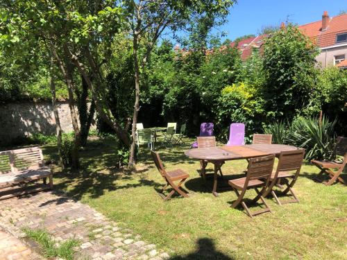 a wooden table and chairs in a yard at Appartement Rosendael proximité plage Malo les bains in Dunkerque