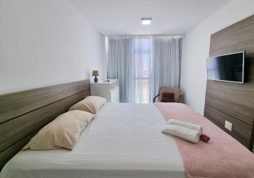 a bedroom with a large white bed with a wooden headboard at Areias do Mar ! 2 Quartos Familia com Varanda A213 in Barra de São Miguel