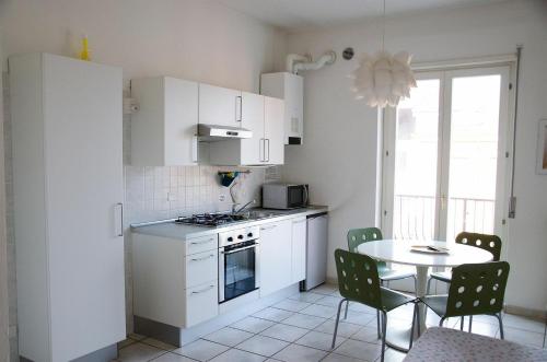 une cuisine avec des placards blancs et une table avec des chaises dans l'établissement Residence Verona Inn, à Vérone
