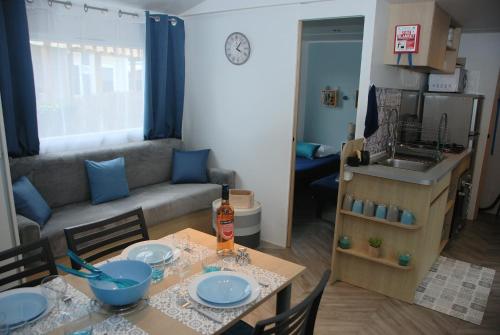 a kitchen and a living room with a table and chairs at Mobilhome climatisé-2ch-terrasse fermée-camping Les Charmettes in Les Mathes