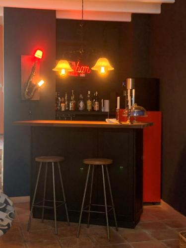 a bar with two stools and a red refrigerator at Las Puertas Del Indiano in Relleu