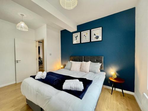 a bedroom with a large bed with a blue wall at City Centre Gem in Southend near the beach, station and parking in Southend-on-Sea