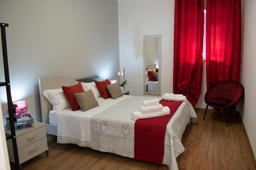 a bedroom with a bed with red curtains and a mirror at M&G holiday house in Matera