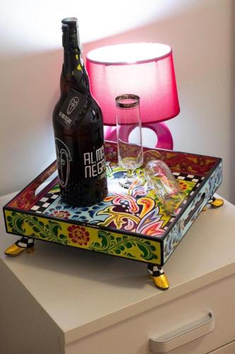 a bottle and glasses on a table with a lamp at M&G holiday house in Matera