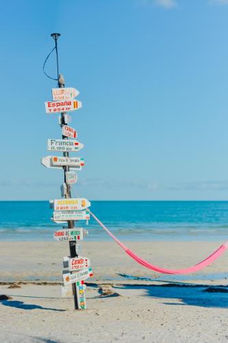 a sign on the beach with many signs on it at Hotel Encanto Holbox Beach Front in Holbox Island