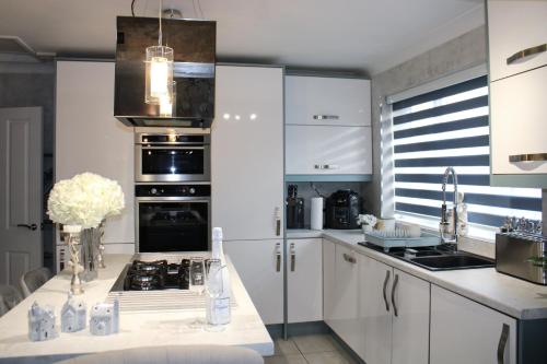 a kitchen with white cabinets and a stove top oven at Stylish 4-Bedroom House near NEC/BHX in Solihull
