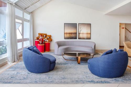 a living room with two blue chairs and a couch at Hotel Estoril in Campos do Jordão