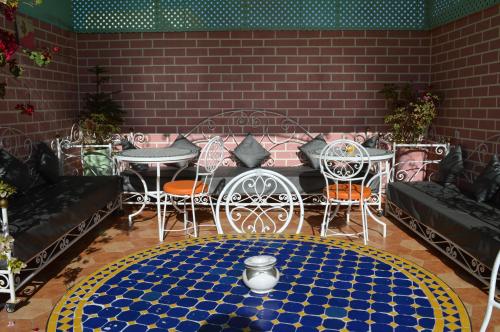 a patio with a table and chairs and a rug at Hotel salem leksor in Marrakech