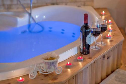 uma banheira com uma garrafa de vinho e copos de vinho em סוויטות פנינת המעיינות em Reẖov