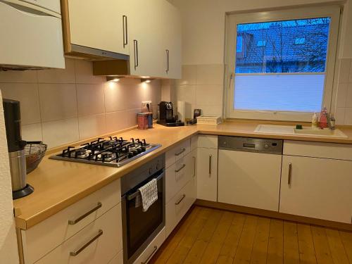 La cuisine est équipée de placards blancs et d'un four avec plaques de cuisson. dans l'établissement Apartment am Palaisgarten, NETFLIX, WLAN, Boxspringbett, à Detmold