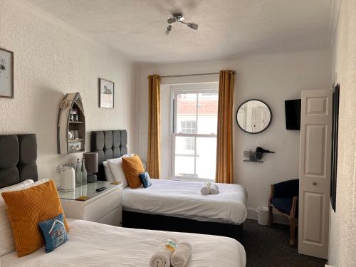 Gumfreston Guest House في تينبي: غرفة فندقية بسريرين ونافذة