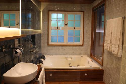 a bathroom with a tub and a sink and a window at Auberge Suisse Pousada in Nova Friburgo