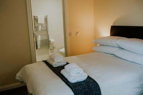 a hotel room with a bed with towels on it at Uist Travel Accommodation in Daliburgh
