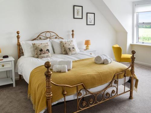 a bedroom with a large bed and a yellow chair at The End Hoose in Whitsome