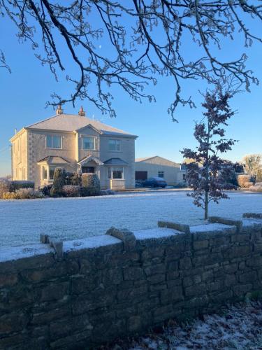 a house with a stone wall and a tree at Inny River Lodge in Rathowen