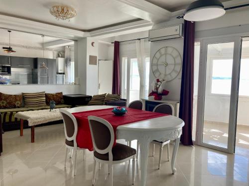 Il comprend un salon doté d'une table blanche avec des chaises et une cuisine. dans l'établissement Confortables location familiale vue sur mer à Sidj Fredj, à Staoueli