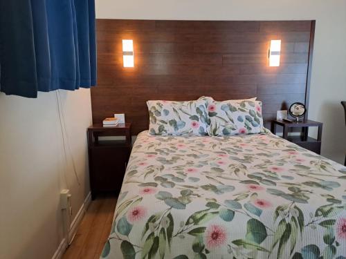 a bedroom with a bed with a floral comforter at Three Island Motel in Bobcaygeon