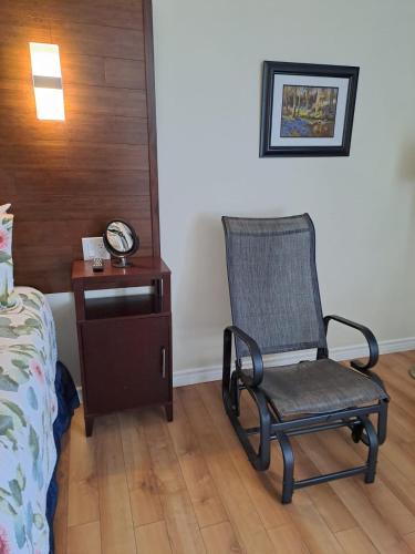 a chair in a room with a bed and a clock at Three Island Motel in Bobcaygeon