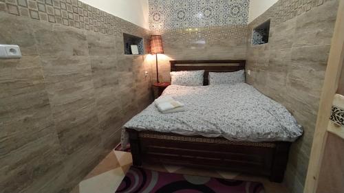 a small bedroom with a bed and a tile wall at Casa Morisca in Sidi Ifni