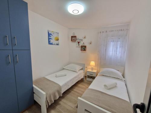 two beds in a small room with a window at Apartments Duje in Split