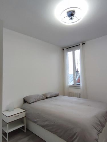 ein weißes Schlafzimmer mit einem Bett und einem Fenster in der Unterkunft La vie en blanc et noir Maisons-Laffitte in Maisons-Laffitte