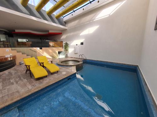 a swimming pool with two yellow chairs and a table at Hotel Alcampo in Querétaro