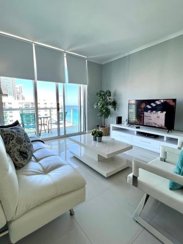 a living room with a white couch and a flat screen tv at Hollywood on Beach Apartment in Hollywood