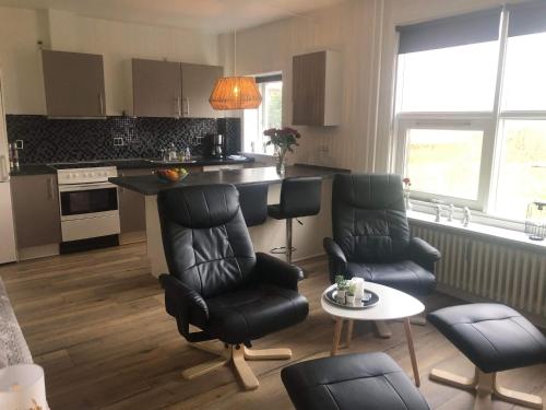 eine Küche mit schwarzen Stühlen, einem Tisch und einer Theke in der Unterkunft Grønnegade - tæt på Esbjerg C in Esbjerg