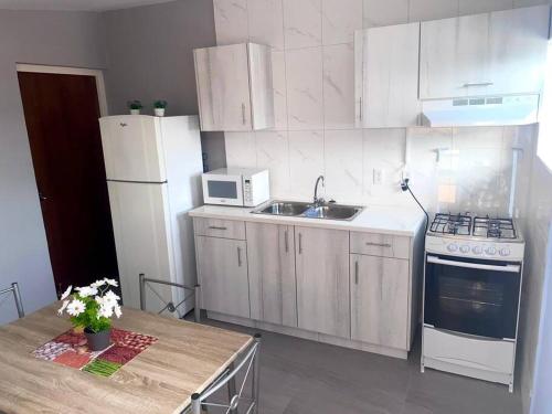 cocina con armarios blancos, fregadero y nevera en Cozy 1-bedroom apartment close to city center en Willemstad