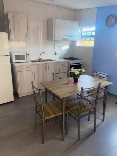 uma cozinha com uma mesa e cadeiras de madeira e uma cozinha com um frigorífico em Cozy 1-bedroom apartment close to city center em Willemstad