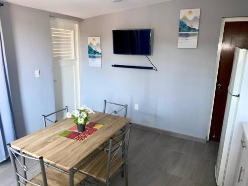 a dining room with a table and a tv on a wall at Cozy 1-bedroom apartment close to city center in Willemstad