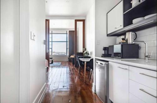 a kitchen with white cabinets and a wooden floor at 1 Bedroom Apartment in CBD in Auckland