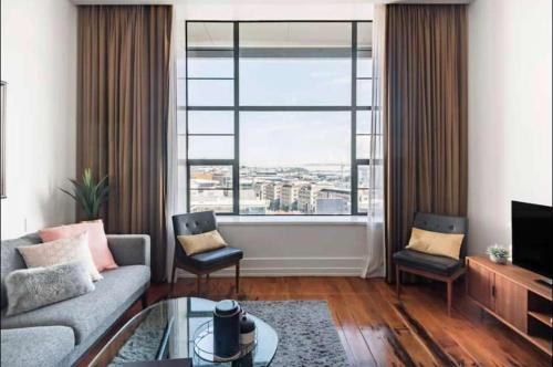 a living room with a couch and a large window at 1 Bedroom Apartment in CBD in Auckland