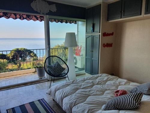 a person laying in bed in a bedroom with a large window at Appartement vue mer panoramique, plage 150M, terrasse, parking privé, clim in Cannes