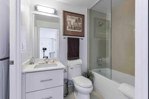 Baño blanco con aseo y lavamanos en Aquarius 2 Bedroom Condo Friday Harbour, en Innisfil