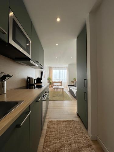une cuisine avec des armoires vertes et un couloir avec une table dans l'établissement Appartement Cap city, au Cap d'Agde