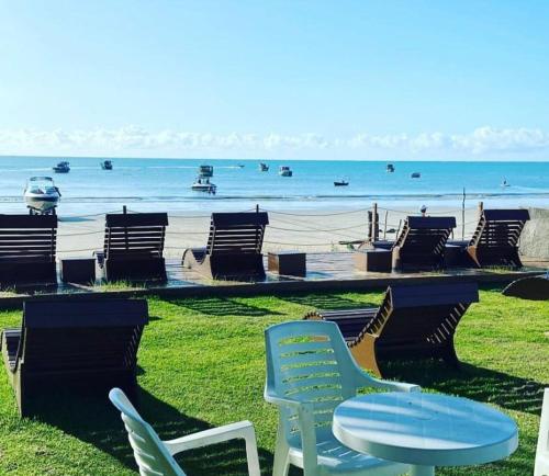 um grupo de cadeiras e uma mesa em frente à praia em Pousada Grandmar, Maragogi em Maragogi