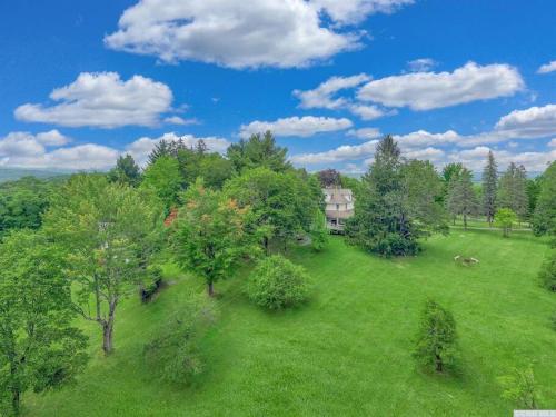 an aerial view of a house in a field with trees at 1850 Catskills Farmhouse on 8 acres in E. Durham in East Durham