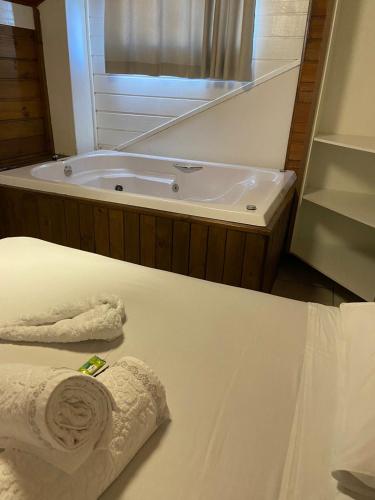 a bathroom with a tub and a bed with a towel at Pousada Recanto do Aconchego in Florianópolis