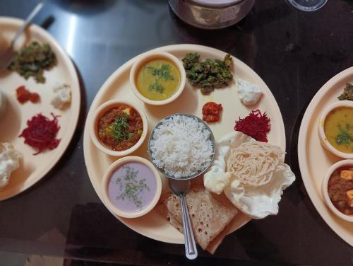 a plate of food with rice and bowls of food at Mhatre Cottage Alibag Mani in Alibaug